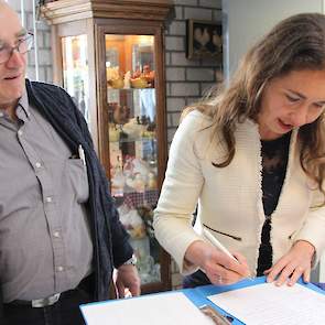 Toon van de Laar is maar wat graag getuige van het zetten van de handtekening door Spierings, in het gastenboek op het bedrijf.